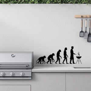 Puede incluir: Una silueta en blanco y negro de la evolución del hombre, que termina con un hombre asando a la parrilla en una barbacoa. La silueta está en una pared blanca sobre una barbacoa de acero inoxidable.