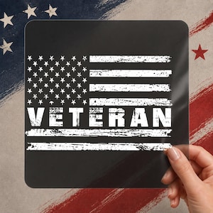 May include: A black square with a distressed white American flag design and the word "VETERAN" in bold white letters. The background features brushstrokes of red, white, and blue.
