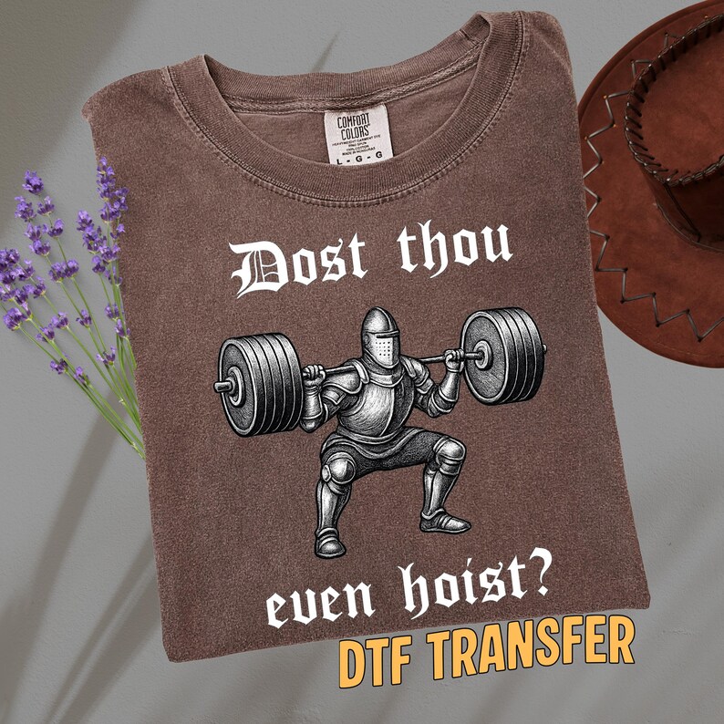 May include: Brown t-shirt with the text "Dost thou even hoist?" and a graphic of a knight lifting weights. The shirt is a Comfort Colors brand and has a vintage look.