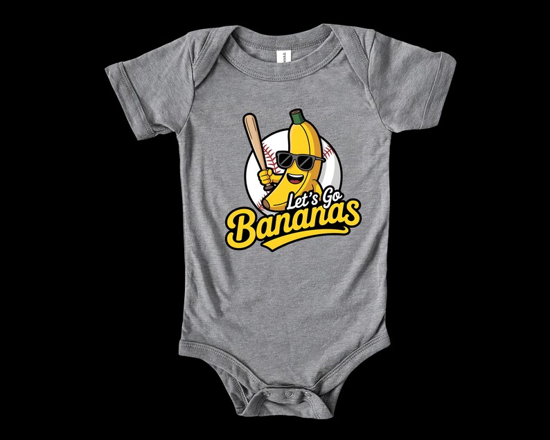 May include: A gray baby bodysuit with a graphic of a smiling banana wearing sunglasses and holding a baseball bat. The text "Let's Go Bananas" is in yellow script. The banana is set against a baseball.