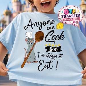 May include: Pale blue t-shirt with the slogan "Anyone can Cook but I'm Here to Eat!" featuring a cartoon rat chef with a wooden spoon. A cheese graphic and a "DTF Transfer Ready to Press" logo are also visible.