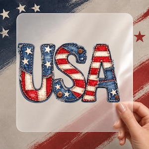 May include: The word "USA" is presented in a patriotic design. The letters are styled to resemble denim, featuring red and white stripes and blue denim with white stars. The letters have a stitched look and are accented with small brown buttons.