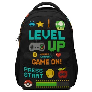 May include: A black backpack featuring a pixelated video game theme. The design includes the text LEVEL UP, GAME ON!, and PRESS START, alongside icons of a game controller, a mushroom, a heart, coins, and a loading bar in vibrant colors.