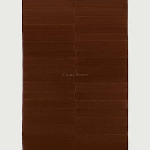May include: A rectangular, brown rug with a textured, horizontal stripe design. The rug has a solid color and a soft appearance. The text "Zaari homes" is printed in the lower center of the rug.