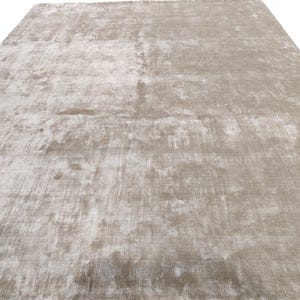 May include: A large, rectangular area rug in a neutral color palette. The rug has a distressed, textured appearance with variations of light beige and gray tones. The overall design is simple and modern, suitable for various interior styles.
