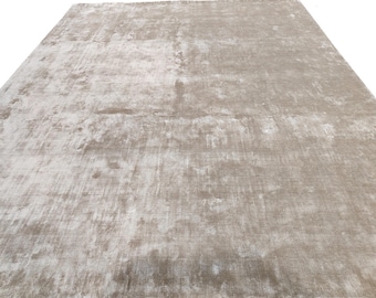 May include: A large, rectangular area rug in a neutral color palette. The rug has a distressed, textured appearance with variations of light beige and off-white, creating a soft, inviting aesthetic. The rug's design suggests a vintage or contemporary style.