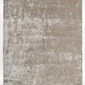 Puede incluir: Una alfombra rectangular con un aspecto desgastado y texturizado. La alfombra presenta una mezcla de tonos neutros, principalmente beige y blanquecino, creando una estética suave y apagada. El diseño tiene un aspecto sutil y envejecido.