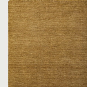 May include: Close-up of a mustard-colored rug with a textured surface. The rug has a soft, plush appearance and a rectangular shape. The color is a warm, earthy tone, suitable for home decor.