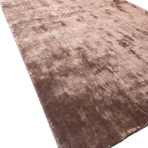May include: A large, rectangular rug in shades of brown and tan. The rug has a soft, textured appearance with subtle variations in color, creating a plush and inviting look. The rug's design is simple, making it suitable for various interior styles.