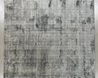 May include: A rectangular, distressed-look rug in shades of gray and charcoal. The rug has a textured appearance with darker patches creating a mottled effect. The overall design is simple and modern, suitable for various interior styles.
