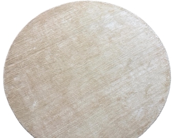 May include: A round, beige rug with a soft, textured surface. The rug has a neutral color palette, making it suitable for various interior design styles. The rug's circular shape adds a touch of elegance to any room.