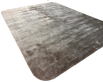 May include: A rectangular area rug featuring a gradient of dark charcoal gray to light silver tones. The surface has a soft, lustrous sheen with a subtle, mottled texture that creates variations in color depth across the entire flat surface.