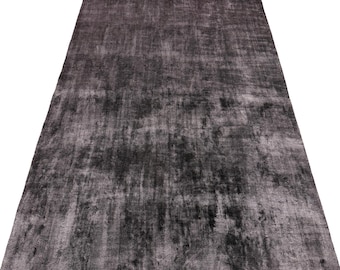 May include: A rectangular area rug featuring a distressed, mottled pattern in shades of charcoal gray, black, and muted silver. The surface displays a textured, weathered appearance with varying color intensity across the entire woven fabric.