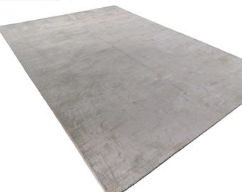 Puede incluir: Una alfombra rectangular grande en un tono gris claro apagado. La alfombra tiene una apariencia texturizada, con sutiles variaciones de tono en su superficie. El diseño general es simple y moderno, adecuado para varios estilos de interiores.