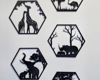 Op de afbeelding: Vijf zwarte metalen wandkunstwerken in een zeshoekige vorm, elk met een andere Afrikaanse dierenscène. De scènes omvatten giraffen, struisvogels, een neushoorn met een kalf, olifanten en leeuwen. De kunstwerken zijn op een witte muur gemonteerd.