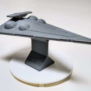 May include: A gray 3D printed model of a Star Wars Interdictor-class Star Destroyer on a gray base with the word "Interdictor" printed on the front.