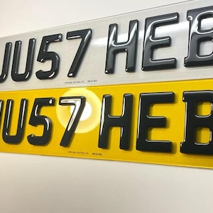 May include: Two car number plates with the letters "JU57 HEB" in black raised letters. The top plate is white and the bottom plate is yellow.