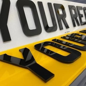 May include: Black acrylic letters spelling out "YOUR REG" on a white background with a yellow background underneath.