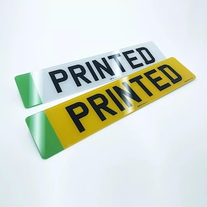 May include: Two rectangular signs with green borders. The top sign is white with black text that reads "PRINTED". The bottom sign is yellow with black text that reads "PRINTED".