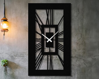 May include: A black rectangular wall clock with Roman numerals. The clock has a geometric design with a central square and radiating lines. The clock hands are white. The clock is mounted on a gray concrete wall.