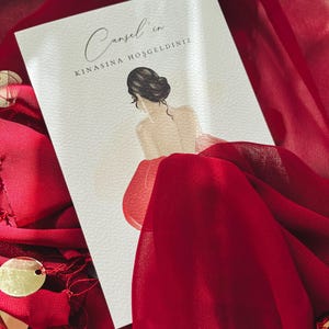 Puede incluir: Una tarjeta blanca con el texto "Cansel'in Kinasina Hosgeldiniz" en caligrafía negra. La tarjeta presenta una ilustración dibujada a mano de una mujer con cabello largo y oscuro que lleva un vestido rojo.