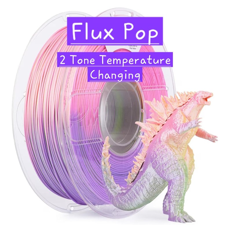 以下が含まれることがあります： ピンク、紫、ライトグリーンのグラデーションが施されたFlux Pop 2 Tone Temperature Changing 3Dプリンター用フィラメントのロール。その横には、質感が細かく鱗のある体で、色が変化するモンスターのフィギュアが置かれています。