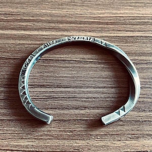 May include: A silver twisted metal bangle bracelet engraved with the names "Michael", "Alice", and "Rosemary".