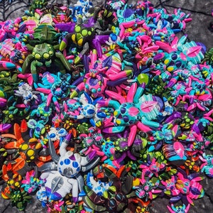 Puede incluir: Una gran colección de figuritas de araña pintadas a mano y coloridas. Las arañas están hechas de una variedad de materiales, incluyendo plástico, madera y metal. Todas son de diferentes tamaños y formas, y algunas tienen detalles intrincados.