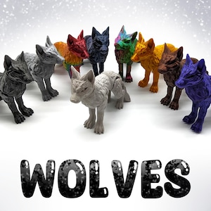 Puede incluir: Una colección de diez figuritas de lobo pintadas a mano en varios colores, incluyendo gris, rojo, azul, verde y amarillo. Las figuritas están dispuestas en círculo sobre una superficie blanca. La palabra "WOLVES" está impresa en letras negras debajo de las figuritas.