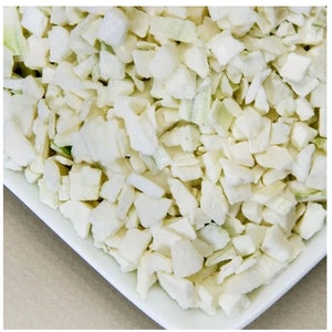 May include: A white bowl filled with small, diced pieces of white and green vegetables. The vegetables appear to be frozen.