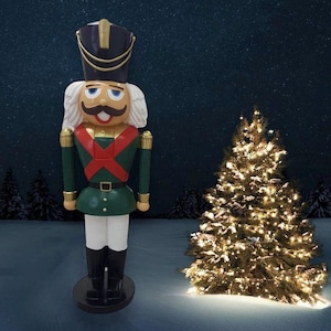 Könnte beinhalten: Eine große, grüne und rote Nussknackerfigur steht vor einem verschneiten Hintergrund mit einem Weihnachtsbaum dahinter. Der Nussknacker hat einen weißen Bart und einen schwarzen Hut mit goldenen Verzierungen.