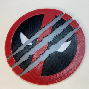 May include: A red and black circular coaster with a white design. The coaster has a cracked or broken design with three gray lines.