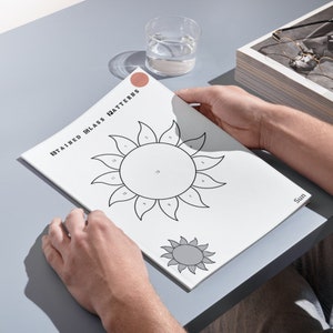 May include: A white booklet with the text "STAINED GLASS PATTERNS" on the cover. The booklet features a black and white illustration of a sun with numbers around the circle. The sun is partially filled in with grey.