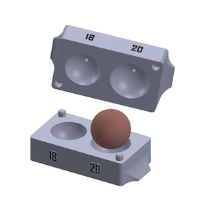 Op de afbeelding: Een tweedelige mal voor het maken van ronde ornamenten. De mal is gemaakt van grijs plastic en heeft twee holtes, gelabeld "18" en "20". Een bruine bol zit in een van de holtes.