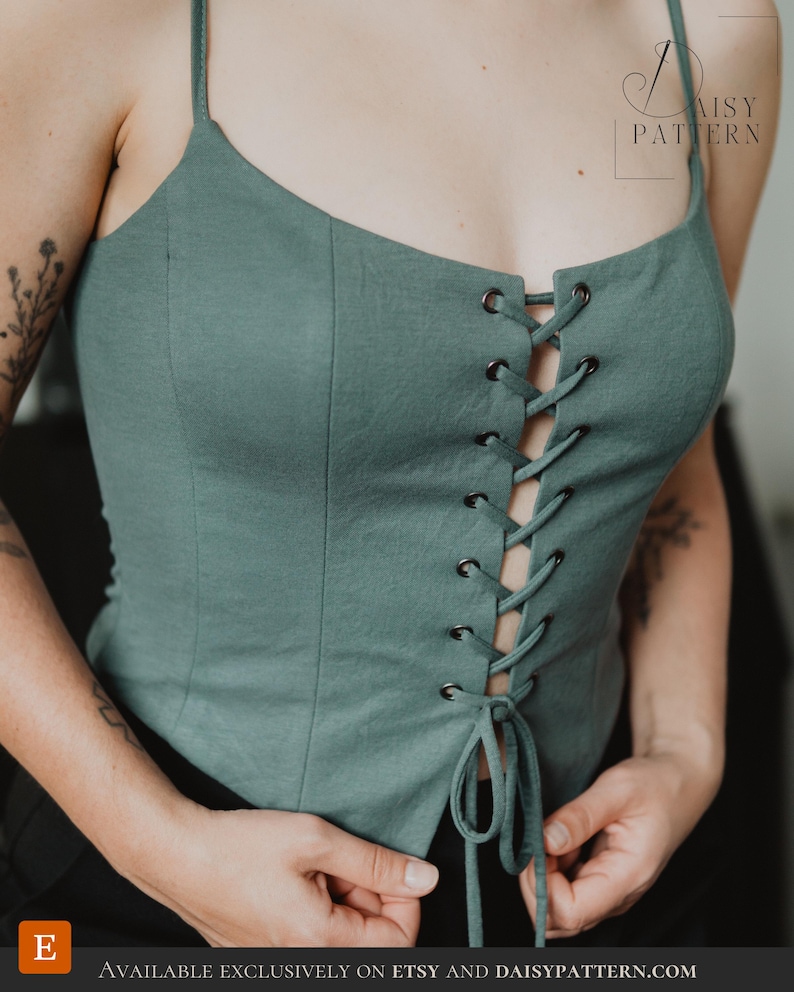 May include: A sage green corset-style top featuring thin spaghetti straps, a sweetheart neckline, and a front lace-up closure with dark metal grommets and matching fabric ties. The text DAISY PATTERN is visible in the upper right corner.