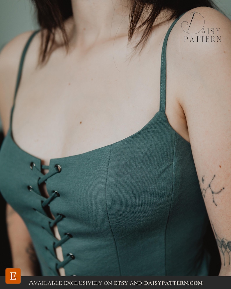 May include: A dark teal camisole top featuring thin spaghetti straps and a front lace-up closure with dark metal grommets. The garment has a fitted bodice with vertical seam detailing. The text DAISY PATTERN is visible in the upper right corner.