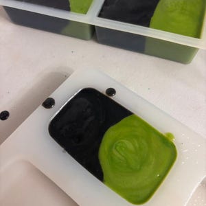 Peut inclure: Gros plan sur la fabrication de savon. Moules &agrave; savon rectangulaires avec du savon noir et vert. Le savon est en cours de versement dans les moules. Le savon est un m&eacute;lange de couleurs noir et vert.