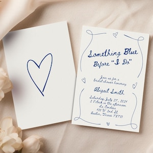 May include: A white card with a blue handwritten heart on it. A second card with a blue handwritten invitation for a bridal shower honoring Abigail Smith. The invitation reads "Something Blue Before "I Do"" and includes the date, time, and location of the event.