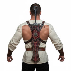 May include: A back view of a person wearing a decorative sword harness with a sword. The harness is burgundy and brown with ornate patterns and a central medallion. The sword has a black handle and a curved blade.