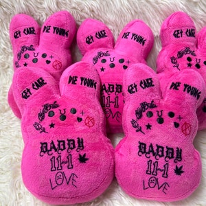May include: Pink plush bunny toys with black text that reads "Get Cake" and "Die Young". The bunnies have various tattoos and the text "Daddy 11-1 Love". These plush toys are a unique gift.