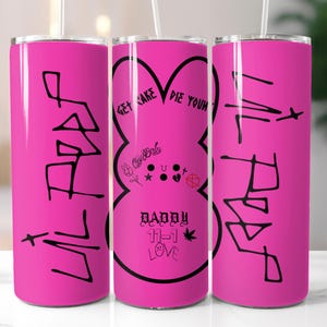 Könnte beinhalten: Drei rosafarbene Edelstahlbecher mit schwarzen Designs. Der mittlere Becher hat ein Herz mit dem Text "Get Cake Die Young" und "Daddy 11-1 Love". Der linke und rechte Becher haben den Text "Lil Peep" in Schwarz.