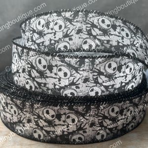 May include: A roll of decorative ribbon featuring a repeating pattern of Jack Skellington faces in black and white. The ribbon has a black stitched edge and is suitable for crafting and holiday decorations.