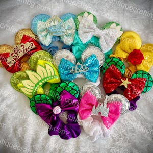 Può includere: Una collezione di dieci paia di orecchie di topo fatte a mano a tema Disney. Le orecchie sono realizzate con vari tessuti e materiali, tra cui paillettes, glitter e raso. Le orecchie sono decorate con vari personaggi Disney, tra cui Ariel, Belle, Cenerentola e Rapunzel.