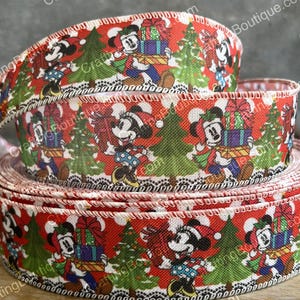 May include: Red Christmas ribbon featuring Mickey and Minnie Mouse carrying gifts and standing near green Christmas trees. The ribbon has a white and black decorative border and is rolled into a stack.