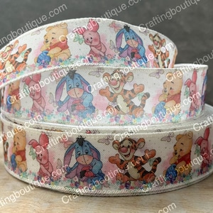 May include: White ribbon with a repeating pattern of cartoon characters from Winnie the Pooh and Disney's classic animated film, The Tigger Movie. The characters include Winnie the Pooh, Tigger, Piglet, Eeyore, and a blue character resembling a donkey.