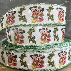 May include: White ribbon with a green border featuring a repeating pattern of Mickey Mouse and Minnie Mouse dressed in red and white holiday outfits with holly leaves.