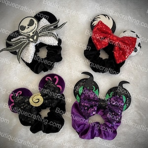 May include: Four black velvet scrunchies with different Halloween-themed character appliques. The scrunchies feature a black and white Jack Skellington, a red and white bow, a black and gold swirl, and a purple and green swirl.
