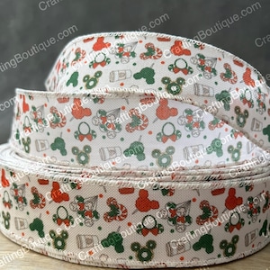 May include: A roll of decorative ribbon with a repeating pattern of red, green, and white holiday-themed icons. The icons include Mickey Mouse heads, candy canes, and other festive elements. The ribbon is beige.