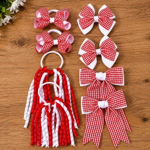 Puede incluir: Una colección de accesorios para el cabello con lazos de tela de cuadros vichy rojos y blancos. El conjunto incluye dos lazos pequeños en gomas elásticas, dos lazos medianos en clips y dos lazos grandes en gomas con largas cintas en espiral.