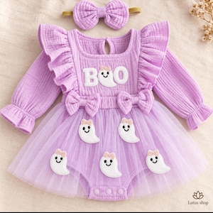 Pode incluir: Um vestido de manga comprida roxo claro com ombros franzidos, saia de tule e fita para o cabelo a combinar. O corpete apresenta o texto BOO com um gráfico de fantasma. Aplicações de fantasmas com laços decoram a saia de tule do vestido.